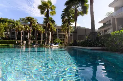 a swimming pool in front of a building with palm trees at JSD Prime Property-Kamala Beach in Surin Beach