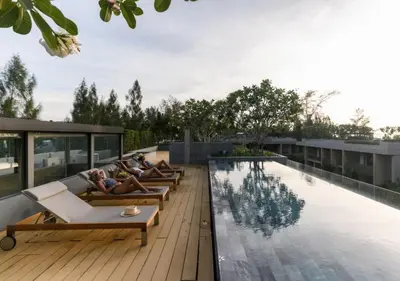 two people laying on lounge chairs next to a swimming pool at JSD Prime Property-Kamala Beach in Surin Beach