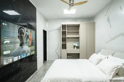 a bedroom with a white bed and a large screen at DreamHouse in Ban Bang Khu