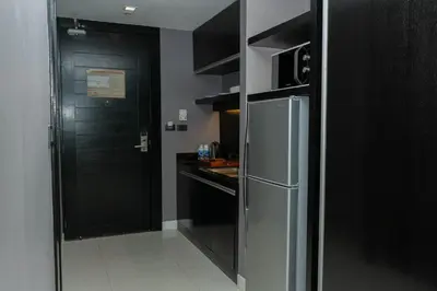 a kitchen with a stainless steel refrigerator and black cabinets at Beachfront and Deluxe Pool Access Patong Phuket in Patong Beach