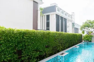 a hedge in front of a building with a swimming pool at Beachfront and Deluxe Pool Access Patong Phuket in Patong Beach