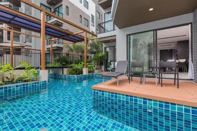 a swimming pool with two chairs and a table on a building at Beachfront and Deluxe Pool Access Patong Phuket in Patong Beach