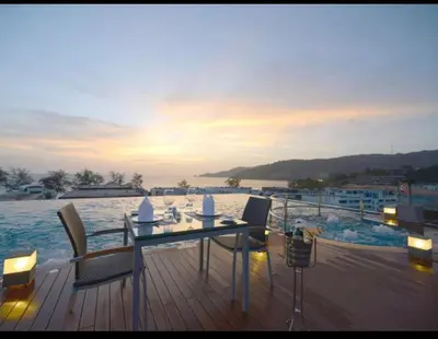 a wooden deck with a table and chairs on a boat at Beachfront and Deluxe Pool Access Patong Phuket in Patong Beach