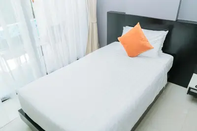 a bedroom with a white bed with an orange pillow at Beachfront and Deluxe Pool Access Patong Phuket in Patong Beach