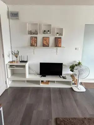 a living room with a television on a white shelf at dcondo Mine Phuket in Kathu