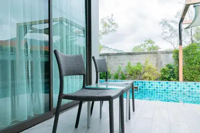 two chairs and a glass table on a balcony at Beachfront Family Pool 1 BR 1 Living Patong Phuket in Patong Beach