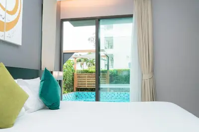 a bedroom with a bed and a large window at Beachfront Family Pool 1 BR 1 Living Patong Phuket in Patong Beach