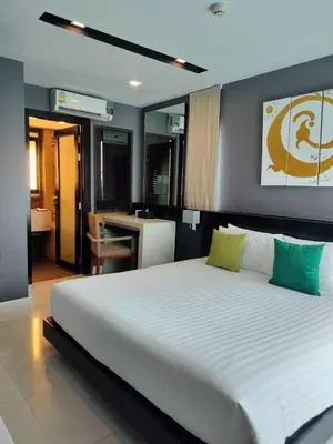 a bedroom with a large white bed with green pillows at Beachfront Family Pool 1 BR 1 Living Patong Phuket in Patong Beach