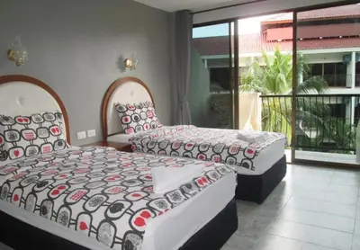 a bedroom with two beds and a balcony at Sunflower Guesthouse in Karon Beach