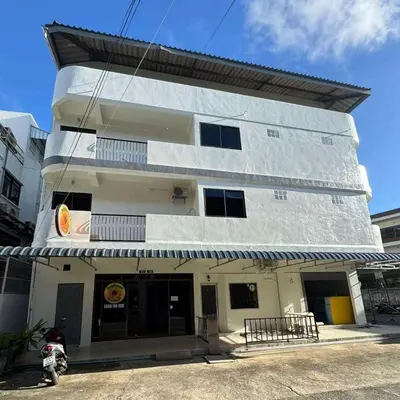 a white building with a scooter parked in front of it at Sunflower Guesthouse in Karon Beach