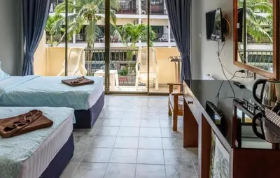 a room with two beds and a television and a balcony at Sunflower Guesthouse in Karon Beach