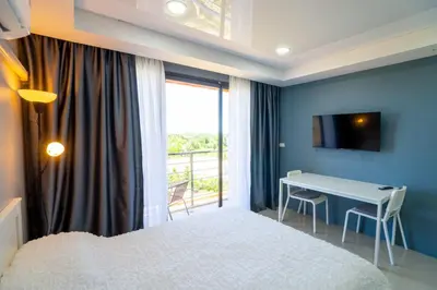 a bedroom with a bed and a desk and a window at White Room in Ban Mai Salae