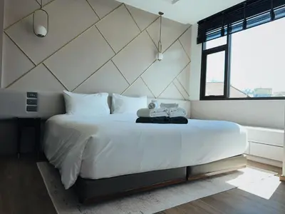 a bedroom with a large white bed and a window at Praud Karon in Karon Beach