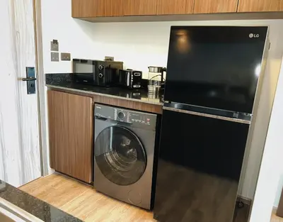 a kitchen with a washing machine and a microwave at Praud Karon in Karon Beach