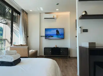 a bedroom with a bed and a tv on the wall at Praud Karon in Karon Beach