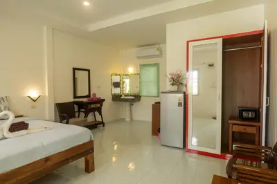 a bedroom with a bed and a refrigerator in it at The Golden Beach Resort Naiyang in Nai Yang Beach