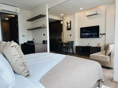 a bedroom with a white bed and a living room at Praud Karon 605 in Karon Beach