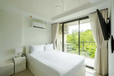 a white bedroom with a large bed and a window at Room 303 Rawai Beach Condo in Nai Harn Beach
