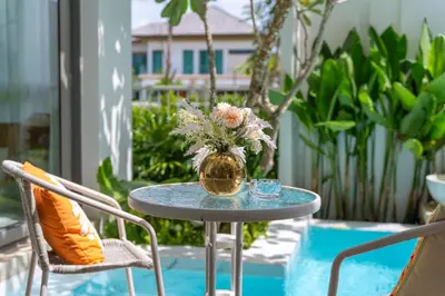 a glass table with a vase of flowers on a patio at \u4e91\u6816\u522b\u9662 Cloudrest Villa in Phuket Town