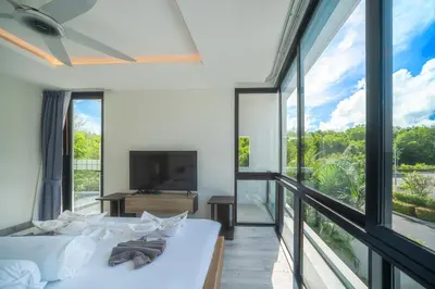 a room with large windows and a bed and a tv at Modern Minimalist 6 Bedroom Light Luxury Villa Private Pool Golf Course Laguna Park in Bang Tao Beach