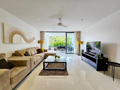 a living room with a couch and a table at Stylish 2-Bedroom Apartment with Pool Access in Surin Beach
