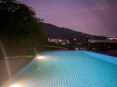 a large swimming pool at night with lights at Viewpoint Villa with Private Infinity Pool - 2BR in Rawai Beach