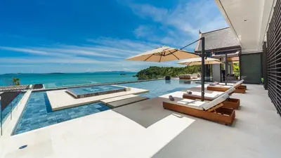 an infinity pool with two lounge chairs and an umbrella at Villa Amarapura in Ko Lek