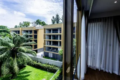 a view from a balcony of a building with a palm tree at Cozy 1 BR beachfront apartment in Bang Tao Beach