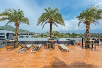 a patio with palm trees and tables and chairs at CityGate Kamala 1BR 3 min Beach in Kamala Beach