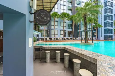 a hotel bar with stools in front of a swimming pool at CityGate Kamala 1BR 3 min Beach in Kamala Beach