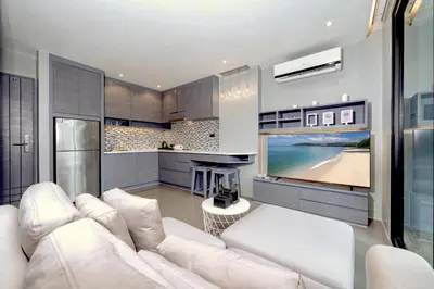 a living room with a white couch and a large screen tv at Tropical & Modern Living - Hill View Tropics Kamala Suite CTG L707, Top Amenities & Beach Fun in Kamala Beach