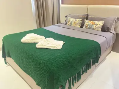 a bed with a green blanket and two towels on it at \u7af9\u5149\u522b\u9662 Bamboo Radiance Villa in Ban Thalat Choeng Thale
