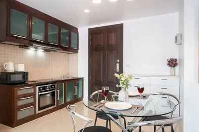 a kitchen with a table and two glasses of wine at Patong612\u7cbe\u88c5\u4e00\u5367\u516c\u5bd3 \u7535\u68af\u6cf3\u6c60\u5065\u8eab\u623f \u6b65\u884c\u591c\u5e02\u6d77\u6ee9 in Patong Beach
