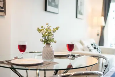 a table with two glasses of wine and a vase with flowers at Patong612\u7cbe\u88c5\u4e00\u5367\u516c\u5bd3 \u7535\u68af\u6cf3\u6c60\u5065\u8eab\u623f \u6b65\u884c\u591c\u5e02\u6d77\u6ee9 in Patong Beach