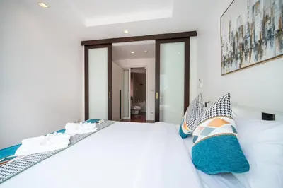 a bedroom with a white bed with blue pillows at Patong612\u7cbe\u88c5\u4e00\u5367\u516c\u5bd3 \u7535\u68af\u6cf3\u6c60\u5065\u8eab\u623f \u6b65\u884c\u591c\u5e02\u6d77\u6ee9 in Patong Beach