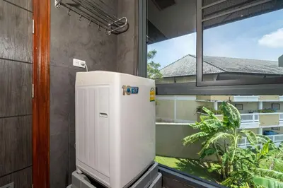 a small white refrigerator in a room with a window at Beautiful 2BR Lakeview Apartment in Laguna in Laguna Phuket