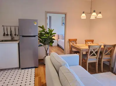 a kitchen and living room with a table and a refrigerator at Endless white 2BR apartment-300m to NaiYang Beach in Nai Yang Beach