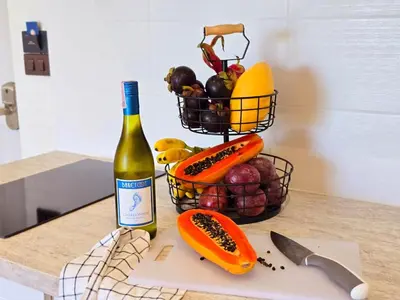 a bottle of wine and a basket of fruit and vegetables at Endless white 2BR apartment-300m to NaiYang Beach in Nai Yang Beach
