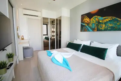 a bedroom with a white bed with a blue towel on it at Cassia Lakeview 1BR Apartments, 10min to Beach in Laguna Phuket