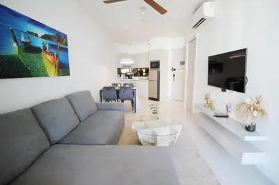 a living room with a couch and a tv at Cassia Lakeview 1BR Apartments, 10min to Beach in Laguna Phuket