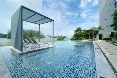 a swimming pool with two lounge chairs next to a building at Cassia Lakeview 1BR Apartments, 10min to Beach in Laguna Phuket
