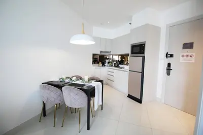 a kitchen with a table with chairs and a refrigerator at Cassia Lakeview 1BR Apartments, 10min to Beach in Laguna Phuket