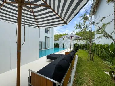 an outdoor patio with an umbrella and a pool at Luxpride 3BR near laguna friendly villa with Garden&pool in Ban Pak Lak