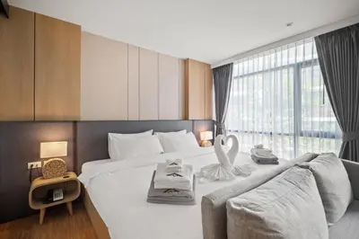 a hotel room with a large bed and a large window at Pool View 1412 Elegant Wyndham Condo in Nai Thon Beach