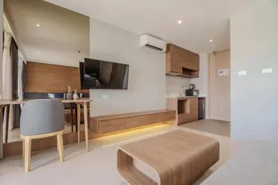 a living room with a television and a table and a chair at Pool View 1412 Elegant Wyndham Condo in Nai Thon Beach