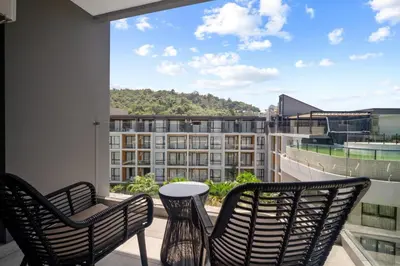 a balcony with two chairs and a view of a building at Pool View 1412 Elegant Wyndham Condo in Nai Thon Beach