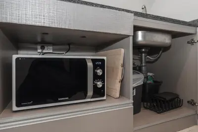 a microwave in a cabinet in a kitchen at C207 Rooftop Pool & King Bed, Walk to Surin Beach in Surin Beach