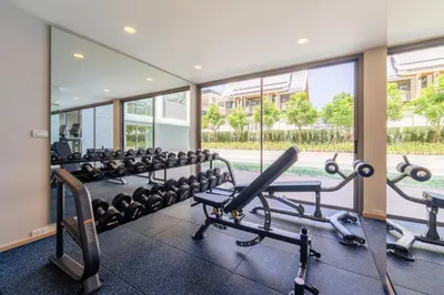 a gym with rows of exercise equipment and a large window at The Ozone Residences Bangtao in Phuket