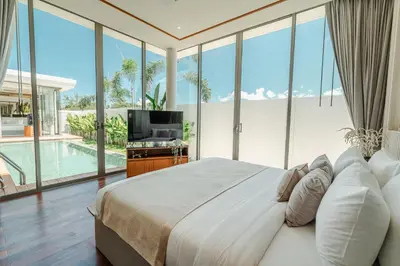 a bedroom with a bed and a tv and glass windows at The Ozone Residences Bangtao in Phuket