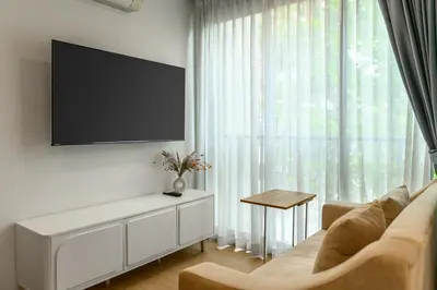 a living room with a couch and a flat screen tv at Zcape 2 Phuket by RESAVA in Bang Tao Beach